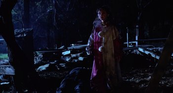 Movie still from “Halloween 4: The Return of Michael Myers” (1988), directed by Dwight H. Little – A person in a costume standing in a dark forest; Medium shot, Over the shoulder angle