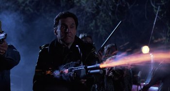 Movie still from “Halloween 4: The Return of Michael Myers” (1988), directed by Dwight H. Little – A man holding a rifle with a bunch of fire coming out of it; Close Up shot, Low angle