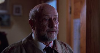 Movie still from “Halloween 4: The Return of Michael Myers” (1988), directed by Dwight H. Little – An old man with a shaved head wearing a suit and tie; Close Up shot, Low angle