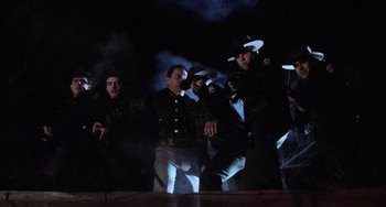 Movie still from “Halloween 5: The Revenge of Michael Myers” (1989), directed by Dominique Othenin-Girard – A group of men in uniform are standing in a dark room; Wide shot, Low angle