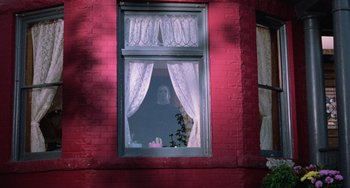 Movie still from “Halloween 5: The Revenge of Michael Myers” (1989), directed by Dominique Othenin-Girard – A woman is looking out of a window at night; Wide shot, Low angle