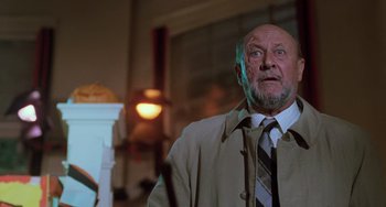 Movie still from “Halloween 5: The Revenge of Michael Myers” (1989), directed by Dominique Othenin-Girard – An older man wearing a suit and tie in a room; Medium shot, Low angle
