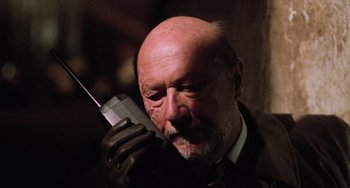 Movie still from “Halloween 5: The Revenge of Michael Myers” (1989), directed by Dominique Othenin-Girard – An older man wearing a suit and tie while talking on a cell phone; Close Up shot, Low angle
