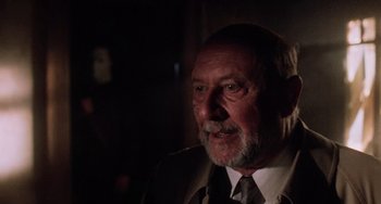 Movie still from “Halloween 5: The Revenge of Michael Myers” (1989), directed by Dominique Othenin-Girard – An older man wearing a suit and a tie; Close Up shot, Over the shoulder angle