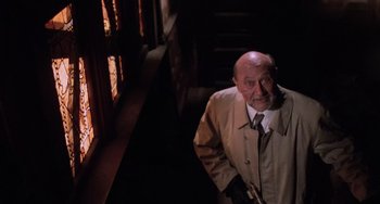Movie still from “Halloween 5: The Revenge of Michael Myers” (1989), directed by Dominique Othenin-Girard – An older man in a trench coat standing in a dark room; Medium shot, Low angle