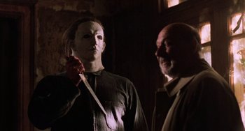 Movie still from “Halloween 5: The Revenge of Michael Myers” (1989), directed by Dominique Othenin-Girard – Two people in a room holding a knife and wearing masks; Medium shot, Low angle