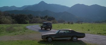 Movie still from “Halloween H20: 20 Years Later” (1998), directed by Steve Miner – An old car is driving down the road in the middle of a field; Extreme Wide shot, High angle