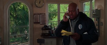Movie still from “Halloween H20: 20 Years Later” (1998), directed by Steve Miner – A man holding papers talking on a phone; Medium shot, High angle