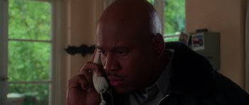 Movie still from “Halloween H20: 20 Years Later” (1998), directed by Steve Miner – A bald man talking on a phone while sitting in a chair; Close Up shot, Low angle