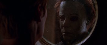 Movie still from “Halloween H20: 20 Years Later” (1998), directed by Steve Miner – A woman looking into a mirror while wearing a mask; Close Up shot, Over the shoulder angle