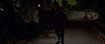 Movie still from “Halloween H20: 20 Years Later” (1998), directed by Steve Miner – A man walking in the dark holding a bat; Wide shot, Low angle