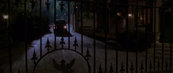 Movie still from “Halloween H20: 20 Years Later” (1998), directed by Steve Miner – A car is parked on the side of the road behind a fence; Extreme Wide shot, High angle