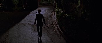 Movie still from “Halloween H20: 20 Years Later” (1998), directed by Steve Miner – A person walking down a street holding a baseball bat; Wide shot, High angle