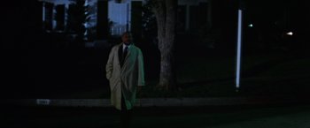 Movie still from “Halloween II” (1981), directed by Rick Rosenthal – A man in a trench coat standing next to a tree at night; Wide shot, Low angle