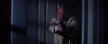 Movie still from “Halloween II” (1981), directed by Rick Rosenthal – A man holding a gun while standing next to a wall; Medium shot, Low angle