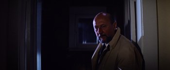 Movie still from “Halloween II” (1981), directed by Rick Rosenthal – A man in a suit and tie standing in a dark room; Close Up shot, Low angle