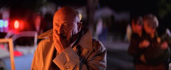 Movie still from “Halloween II” (1981), directed by Rick Rosenthal – An older man in a trench coat is holding his hand to his face; Close Up shot, Low angle
