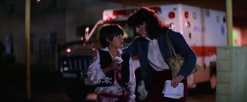 Movie still from “Halloween II” (1981), directed by Rick Rosenthal – A woman and a boy are standing next to each other on the street; Medium shot, Over the shoulder angle