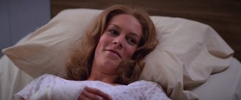 Movie still from “Halloween II” (1981), directed by Rick Rosenthal – A woman laying in a bed smiling at the camera; Close Up shot, High angle