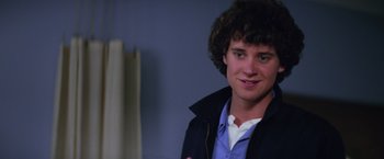 Movie still from “Halloween II” (1981), directed by Rick Rosenthal – A young man with curly brown hair wearing a blue shirt; Close Up shot, Low angle