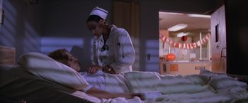 Movie still from “Halloween II” (1981), directed by Rick Rosenthal – A woman in a nurse's uniform tending to a patient in a hospital bed; Medium shot, Low angle