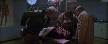 Movie still from “Halloween II” (1981), directed by Rick Rosenthal – Three people in a room with a dead body in a box; Medium shot, Over the shoulder angle