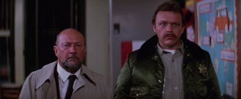 Movie still from “Halloween II” (1981), directed by Rick Rosenthal – Two men standing next to each other in front of a wall; Medium shot, Low angle