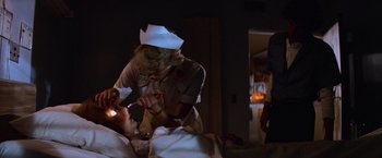 Movie still from “Halloween II” (1981), directed by Rick Rosenthal – A woman in a nurse's uniform is playing with a child in a hospital bed; Close Up shot, Over the shoulder angle