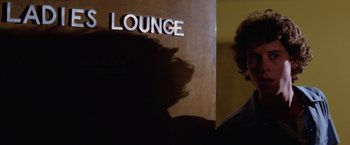 Movie still from “Halloween II” (1981), directed by Rick Rosenthal – A man standing in front of a sign that says " lounge "; Close Up shot, Over the shoulder angle