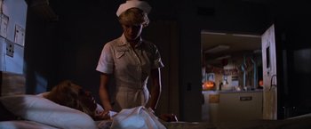 Movie still from “Halloween II” (1981), directed by Rick Rosenthal – A woman standing next to a bed in a room; Medium shot, Over the shoulder angle