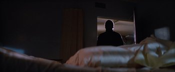 Movie still from “Halloween II” (1981), directed by Rick Rosenthal – A man standing in a dark room looking out a window; Wide shot, Low angle