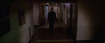 Movie still from “Halloween II” (1981), directed by Rick Rosenthal – A man wearing a gas mask walking down a hallway; Wide shot, Low angle