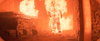 Movie still from “Halloween II” (1981), directed by Rick Rosenthal – A person walking through a fire in a room; Wide shot, Low angle