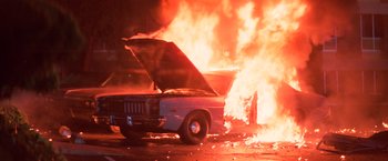 Movie still from “Halloween III: Season of the Witch” (1982), directed by Tommy Lee Wallace – A car is on fire with its hood open; Wide shot, High angle