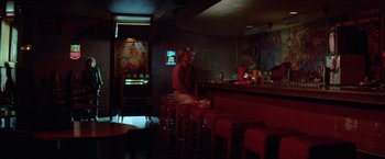 Movie still from “Halloween III: Season of the Witch” (1982), directed by Tommy Lee Wallace – A man sitting at a bar smoking a cigarette; Wide shot, Over the shoulder angle