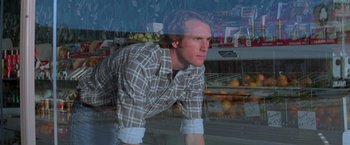 Movie still from “Halloween III: Season of the Witch” (1982), directed by Tommy Lee Wallace – A man is looking out of a store window; Medium shot, Low angle