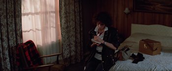 Movie still from “Halloween III: Season of the Witch” (1982), directed by Tommy Lee Wallace – A person writing on a piece of paper in front of a window; Medium shot, High angle