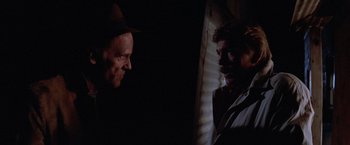 Movie still from “Halloween III: Season of the Witch” (1982), directed by Tommy Lee Wallace – Two men are standing in a dimly - lit room; Close Up shot, Over the shoulder angle
