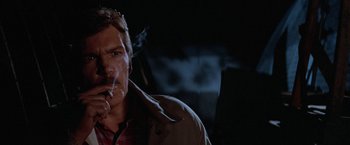 Movie still from “Halloween III: Season of the Witch” (1982), directed by Tommy Lee Wallace – A man smoking a cigarette while wearing a brown jacket; Close Up shot, Low angle