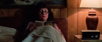 Movie still from “Halloween III: Season of the Witch” (1982), directed by Tommy Lee Wallace – A woman is reading a book in a bed; Medium shot, High angle