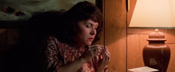 Movie still from “Halloween III: Season of the Witch” (1982), directed by Tommy Lee Wallace – A woman in a red shirt is holding a cigarette; Close Up shot, High angle