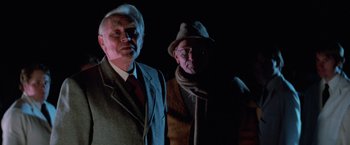 Movie still from “Halloween III: Season of the Witch” (1982), directed by Tommy Lee Wallace – Two older men standing next to each other in the dark; Medium shot, Low angle