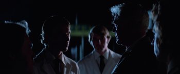 Movie still from “Halloween III: Season of the Witch” (1982), directed by Tommy Lee Wallace – A group of men standing next to each other in the dark; Close Up shot, Over the shoulder angle