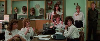 Movie still from “Halloween III: Season of the Witch” (1982), directed by Tommy Lee Wallace – A group of women sitting at a table with a typewriter; Medium shot, Over the shoulder angle