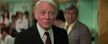 Movie still from “Halloween III: Season of the Witch” (1982), directed by Tommy Lee Wallace – An older man wearing a suit and tie; Close Up shot, Over the shoulder angle