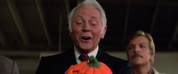 Movie still from “Halloween III: Season of the Witch” (1982), directed by Tommy Lee Wallace – An older man in a black suit and white hair looking at an orange pumpkin; Close Up shot, Low angle