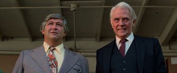 Movie still from “Halloween III: Season of the Witch” (1982), directed by Tommy Lee Wallace – Two men in business suits standing next to each other; Close Up shot, Low angle