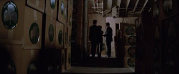 Movie still from “Halloween III: Season of the Witch” (1982), directed by Tommy Lee Wallace – Three men are standing in a room full of boxes; Wide shot, High angle