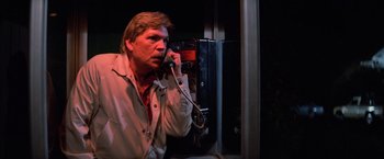 Movie still from “Halloween III: Season of the Witch” (1982), directed by Tommy Lee Wallace – A man talking on a phone in a dark room; Close Up shot, Low angle