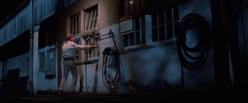Movie still from “Halloween III: Season of the Witch” (1982), directed by Tommy Lee Wallace – A man standing in front of a building next to a fire hydrant; Wide shot, Low angle